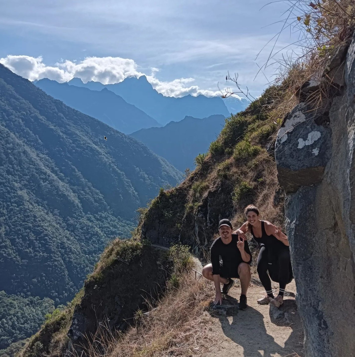 Two hikers on a mountain trail with scenic view of peaks